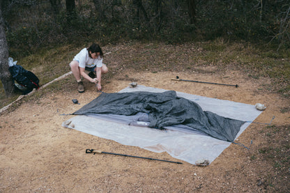Person setting up a tent on a campsite